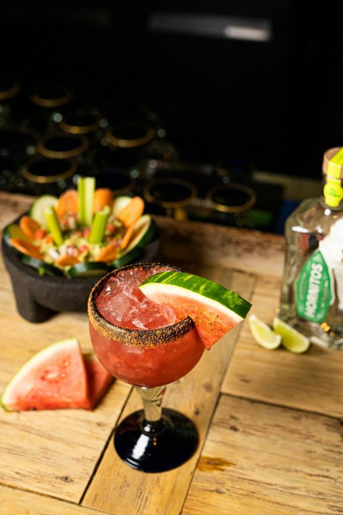Craft margarita with fresh watermelon in cozy bar speakeasy atmosphere.