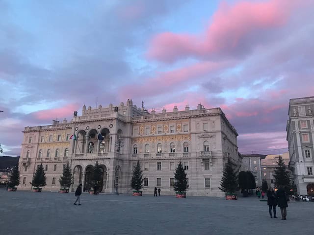 Baroque building on the main plaza in Trieste at sunset with pink clounds in the sky.